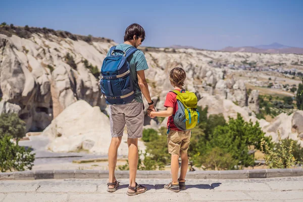 stock image Father and son tourists exploring valley with rock formations and fairy caves near Goreme in Cappadocia Turkey.