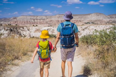 Baba ve oğul turistler Kapadokya 'da Goreme yakınlarında kaya oluşumları ve peri mağaralarıyla vadiyi keşfediyorlar..