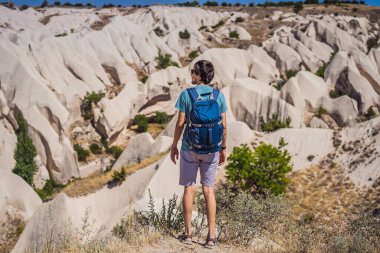 Kapadokya 'da Goreme yakınlarında kaya oluşumları ve peri mağaralarıyla vadiyi keşfeden genç adam.