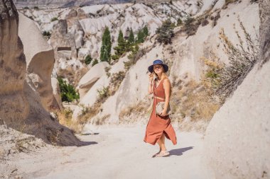 Kapadokya 'da Goreme yakınlarında kaya oluşumları ve peri mağaralarıyla vadiyi keşfeden genç bir kadın..
