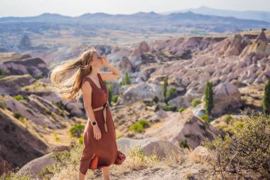 Kapadokya 'da Goreme yakınlarında kaya oluşumları ve peri mağaralarıyla vadiyi keşfeden genç bir kadın..