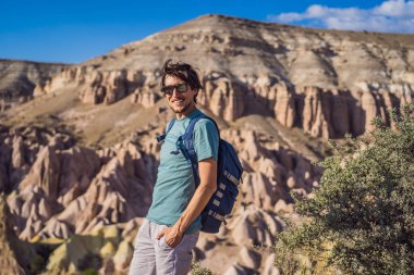 Kapadokya 'da Goreme yakınlarında kaya oluşumları ve peri mağaralarıyla vadiyi keşfeden genç adam.