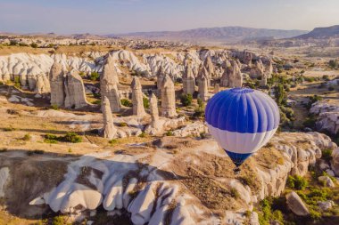 Nevsehir, Goreme, Kapadokya 'daki peri bacaları vadisinde uçan renkli sıcak hava balonları. Yeraltı şehri ve balonlu turizmin muhteşem panoramik görüntüsü. Yüksek kalite.