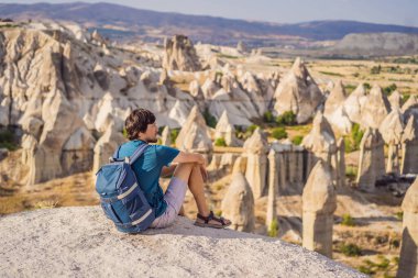 Kapadokya 'da Goreme yakınlarında kaya oluşumları ve peri mağaralarıyla vadiyi keşfeden genç adam.