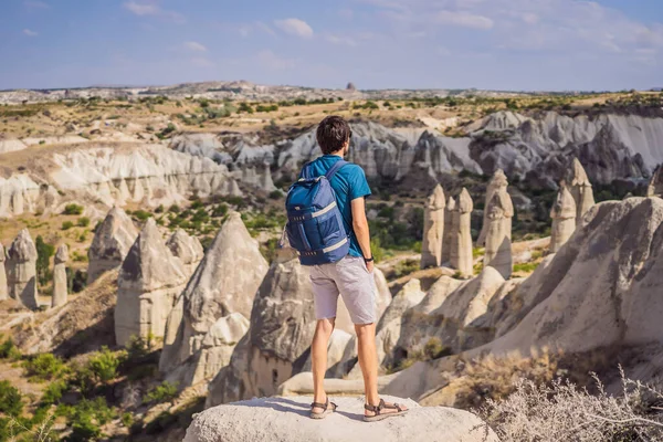 Kapadokya 'da Goreme yakınlarında kaya oluşumları ve peri mağaralarıyla vadiyi keşfeden genç adam.