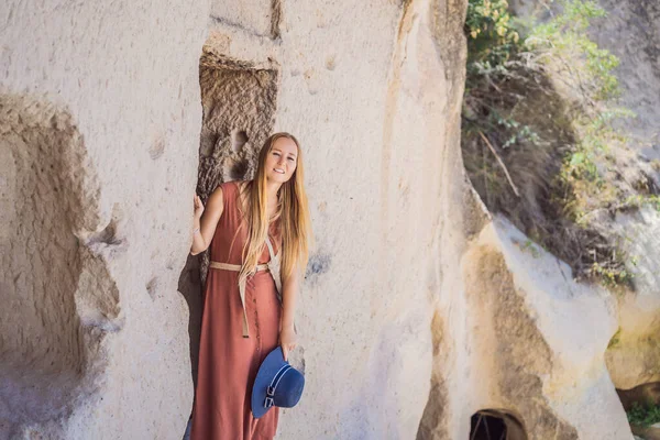 Kapadokya 'da Goreme yakınlarında kaya oluşumları ve peri mağaralarıyla vadiyi keşfeden genç bir kadın..