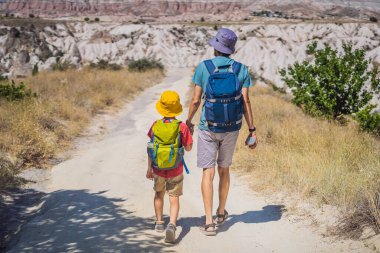 Baba ve oğul turistler Kapadokya 'da Goreme yakınlarında kaya oluşumları ve peri mağaralarıyla vadiyi keşfediyorlar..