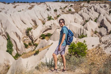 Kapadokya 'da Goreme yakınlarında kaya oluşumları ve peri mağaralarıyla vadiyi keşfeden genç adam.