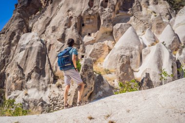 Kapadokya 'da Goreme yakınlarında kaya oluşumları ve peri mağaralarıyla vadiyi keşfeden genç adam.
