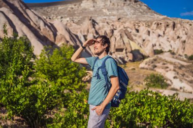 Kapadokya 'da Goreme yakınlarında kaya oluşumları ve peri mağaralarıyla vadiyi keşfeden genç adam.