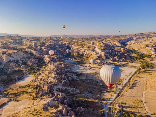 Nevsehir, Goreme, Kapadokya 'daki peri bacaları vadisinde uçan renkli sıcak hava balonları. Yeraltı şehri ve balonlu turizmin muhteşem panoramik görüntüsü. Yüksek kalite.