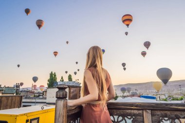 Kapadokya, Türkiye 'de sıcak hava balonlarına bakan turist kadın. İyi yolculuklar hindi konsepti. Dağın tepesinde harika manzaranın tadını çıkaran bir kadın.