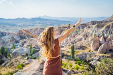 Kapadokya 'da Goreme yakınlarında kaya oluşumları ve peri mağaralarıyla vadiyi keşfeden genç bir kadın..