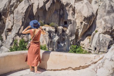 Kapadokya 'da Goreme yakınlarında kaya oluşumları ve peri mağaralarıyla vadiyi keşfeden genç bir kadın..