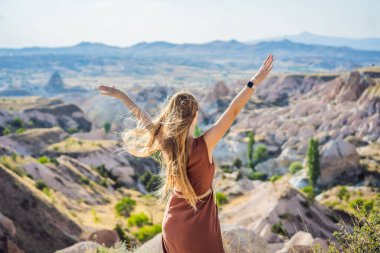 Kapadokya 'da Goreme yakınlarında kaya oluşumları ve peri mağaralarıyla vadiyi keşfeden genç bir kadın..