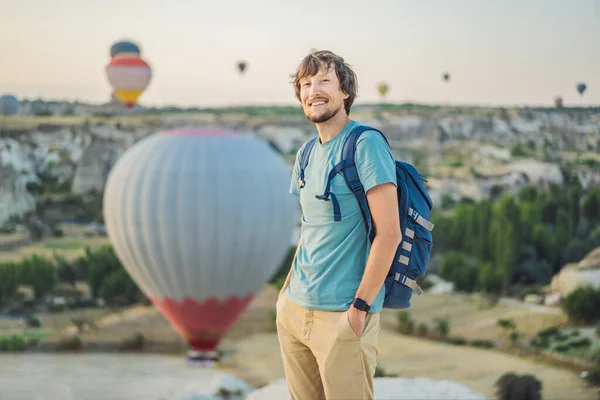 Tourist man looking at hot air balloons in Cappadocia, Turkey. Happy Travel in Turkey concept. Man on a mountain top enjoying wonderful view.