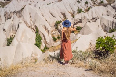 Kapadokya 'da Goreme yakınlarında kaya oluşumları ve peri mağaralarıyla vadiyi keşfeden genç bir kadın..