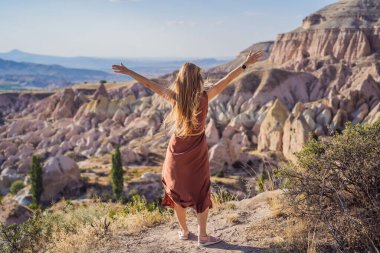 Kapadokya 'da Goreme yakınlarında kaya oluşumları ve peri mağaralarıyla vadiyi keşfeden genç bir kadın..