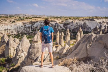 Kapadokya 'da Goreme yakınlarında kaya oluşumları ve peri mağaralarıyla vadiyi keşfeden genç adam.