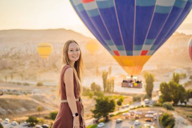 Kapadokya, Türkiye 'de sıcak hava balonlarına bakan turist kadın. İyi yolculuklar hindi konsepti. Dağın tepesinde harika manzaranın tadını çıkaran bir kadın.