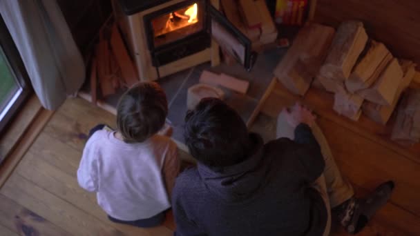 一个年轻人和他的小儿子在家里生火 他们在一间朦胧的小木屋里度假 寒假概念 — 图库视频影像