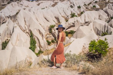 Kapadokya 'da Goreme yakınlarında kaya oluşumları ve peri mağaralarıyla vadiyi keşfeden genç bir kadın..