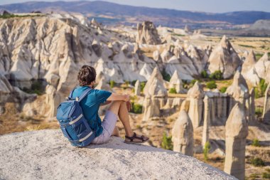 Kapadokya 'da Goreme yakınlarında kaya oluşumları ve peri mağaralarıyla vadiyi keşfeden genç adam.