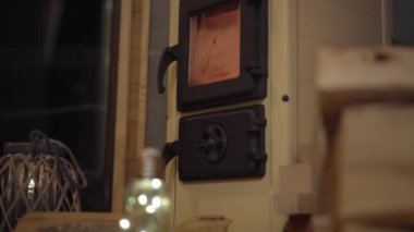 Gece sahnesi. Yanan odunlu yerli bir soba. Küçük sıcacık ahşap ev. Kış tatili konsepti.