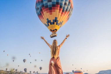 Kapadokya, Türkiye 'de sıcak hava balonlarına bakan turist kadın. İyi yolculuklar hindi konsepti. Dağın tepesinde harika manzaranın tadını çıkaran bir kadın.