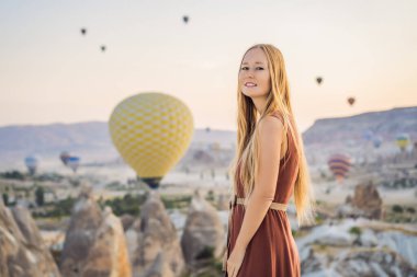 Kapadokya, Türkiye 'de sıcak hava balonlarına bakan turist kadın. İyi yolculuklar hindi konsepti. Dağın tepesinde harika manzaranın tadını çıkaran bir kadın.