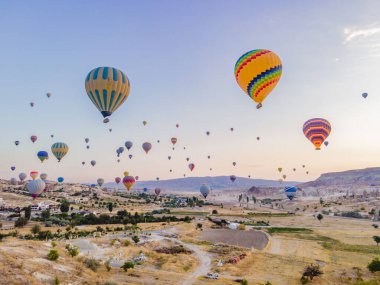 Nevsehir, Goreme, Kapadokya 'daki peri bacaları vadisinde uçan renkli sıcak hava balonları. Yeraltı şehri ve balonlu turizmin muhteşem panoramik görüntüsü. Yüksek kalite.
