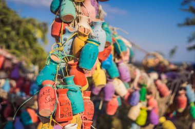 Dilek ağacı. Üzerinde yazılar olan küçük renkli sürahiler, bir ağacın dallarında sallanan dilekler, kum kalıntıları ve mavi gökyüzü..