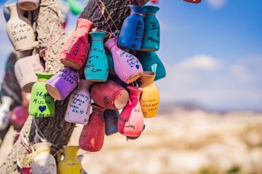 Dilek ağacı. Üzerinde yazılar olan küçük renkli sürahiler, bir ağacın dallarında sallanan dilekler, kum kalıntıları ve mavi gökyüzü..