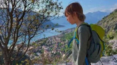 Little boy is walking down from the top of the castle over the city of Kotor in Montenegro. An ancient rocky road leads to the top of the mountain. Slowmotion video.