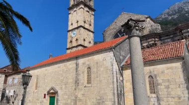 Walking through the charming coastal town of Perast in Montenegro. Strolling along its cobblestone streets lined with historic buildings, including a stunning cathedral with a towering bell tower