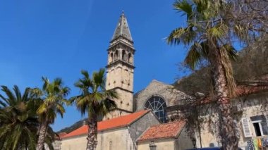 Walking through the charming coastal town of Perast in Montenegro. Strolling along its cobblestone streets lined with historic buildings, including a stunning cathedral with a towering bell tower