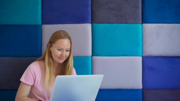 一个年轻的女人在她的笔记本电脑上工作时散发着激情和动力 周围是一个独特而迷人的灰色和蓝色矩形背景 抽象的设计为这一动态发展奠定了基础 — 图库视频影像
