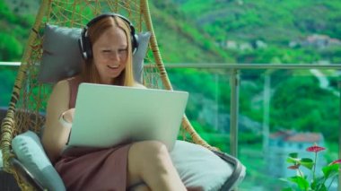 Balkonda genç bir kadın, göz kamaştırıcı dağ manzarası ile çevrili. Sallanan bir sandalyede rahat bir şekilde dizüstü bilgisayarla konuşuyor. Gösteri teknolojisi, iletişim ya da uzak çalışma projeleri için mükemmel.