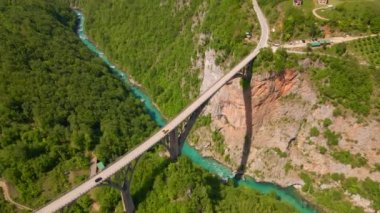 This stunning aerial stock video captures the breathtaking beauty of the Djurdjevica Tara Bridge in Montenegro. Shot during the summer, the bright blue sky and lush green landscape provide the perfect