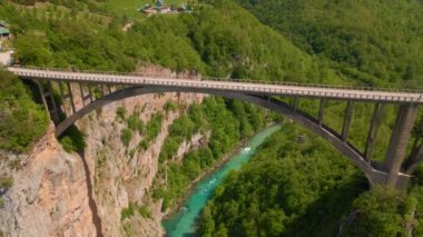 This stunning aerial stock video captures the breathtaking beauty of the Djurdjevica Tara Bridge in Montenegro. Shot during the summer, the bright blue sky and lush green landscape provide the perfect