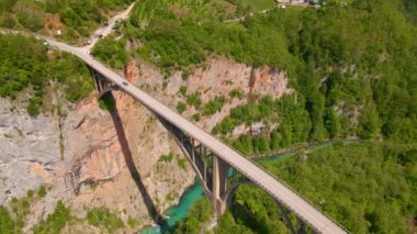 This stunning aerial stock video captures the breathtaking beauty of the Djurdjevica Tara Bridge in Montenegro. Shot during the summer, the bright blue sky and lush green landscape provide the perfect