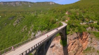 This stunning aerial stock video captures the breathtaking beauty of the Djurdjevica Tara Bridge in Montenegro. Shot during the summer, the bright blue sky and lush green landscape provide the perfect