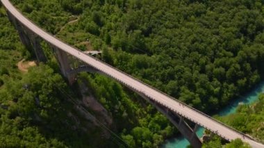 This stunning aerial stock video captures the breathtaking beauty of the Djurdjevica Tara Bridge in Montenegro. Shot during the summer, the bright blue sky and lush green landscape provide the perfect