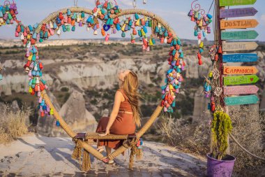 Kapadokya 'da Goreme yakınlarında kaya oluşumları ve peri mağaraları olan vadiyi keşfeden genç bir kadın. Dilek ağacı. Üzerinde yazılar olan küçük renkli sürahiler, bir ağacın dallarında asılı dilekler.