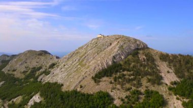 This stock video showcases the breathtaking aerial footage of the Njegos Mausoleum located at the top of the Jezerski peak in Montenegro. The mausoleum is a stunning architectural masterpiece