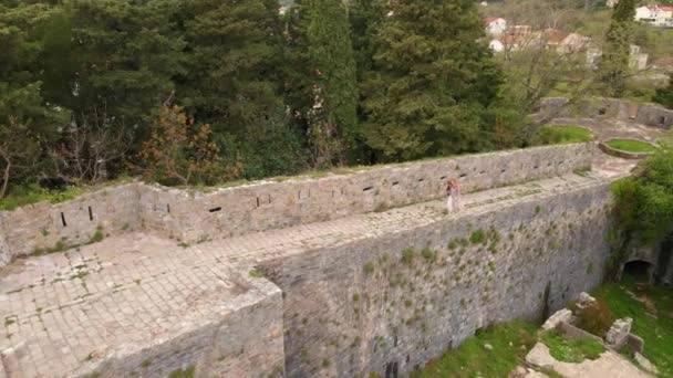 スローモーション空撮ビデオ 若い女性と彼女の息子の観光客は ハーセグ ノヴィの要塞スペイン語または要塞を訪問します 彼らは砦の壁を歩く モンテネグロへの旅行 — ストック動画