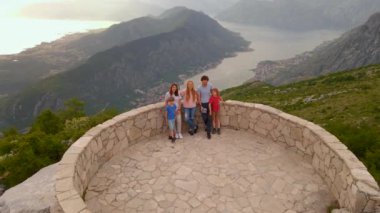 This drone shot captures a group of friends enjoying the breathtaking views of the Boka-Kotor and Tivat bays in Montenegro. They are on a road trip, stand on a view point and take in the gorgeous