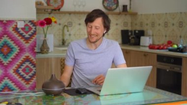 The video features a young man sitting at a desk in his apartment, working on his laptop. A working electric aromatherapy diffuser is seen to the side of him, emitting a soothing fragrance. The video