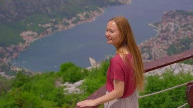 Karadağ 'ın çarpıcı Kotor Körfezi' ne bakan genç bir kadın görülüyor. Işıl ışıl mavi sulara ve arka planda yuva yapmış eski Kotor kasabasına bakıyor.