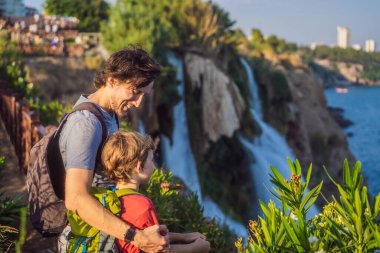 Baba ve oğul turistler Antalya 'daki Duden şelalesinin arka planında. Türkiye 'nin ünlü yerleri. Aşağı Duden Şelaleleri 40 metreden Akdeniz 'e düşen kayalık bir uçurumdan inanılmaz bir şekilde düşüyor.